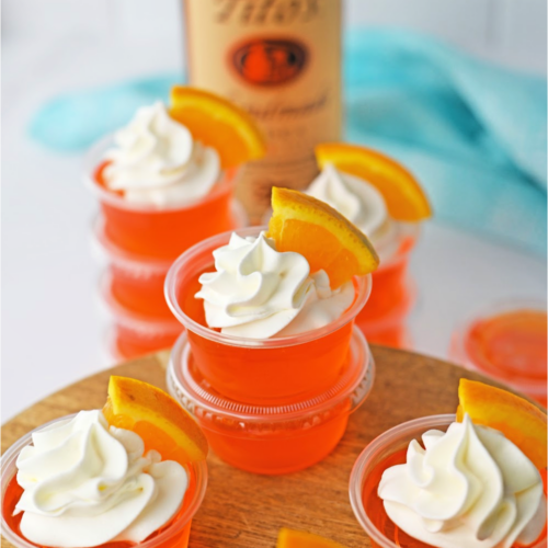 orange jello shots stacked with a whipped cream topping and slice or orange