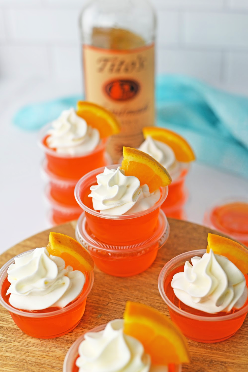 orange jello shots stacked with a whipped cream topping and slice or orange