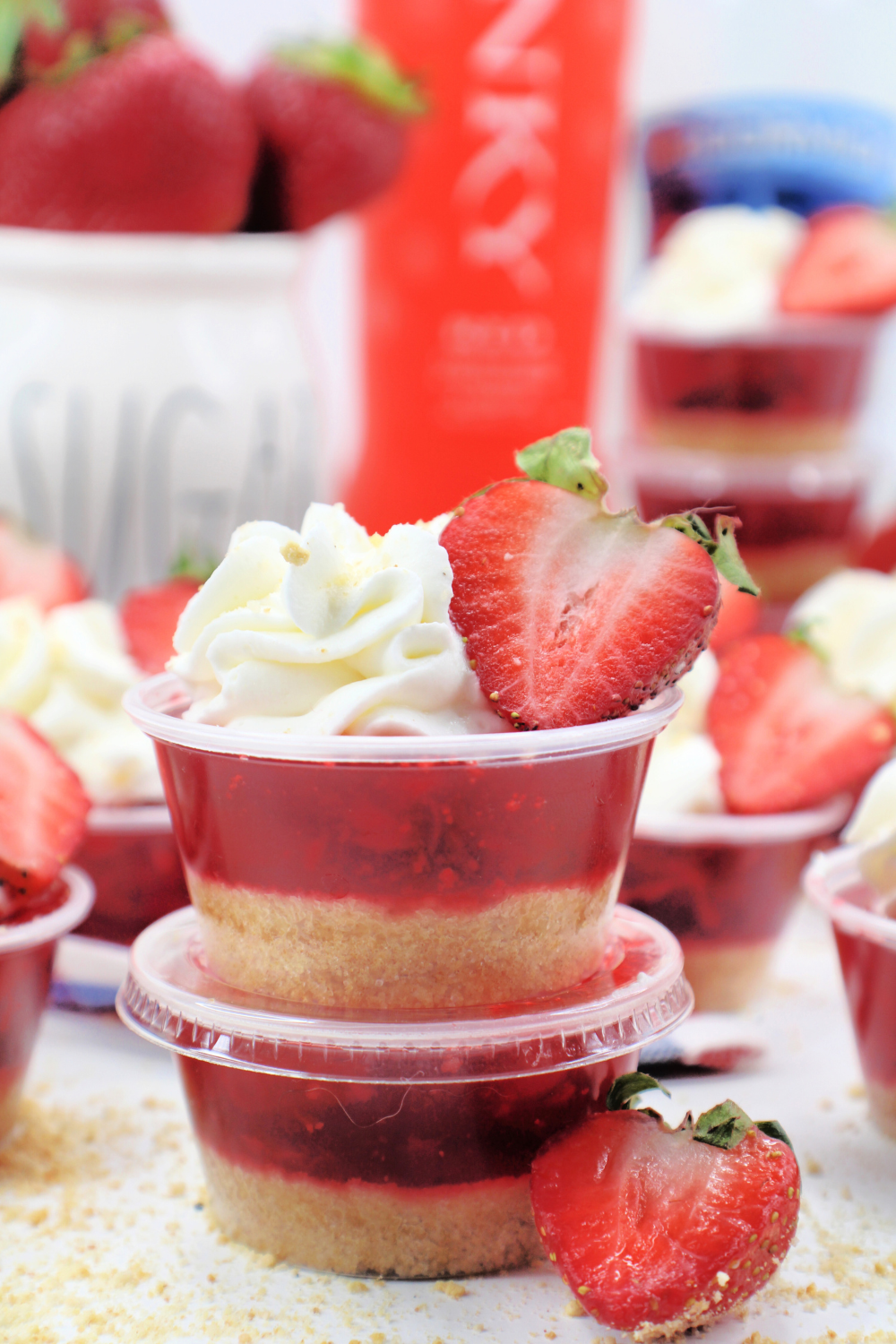 Stacked strawberry pie jello shots with more shots in the background.