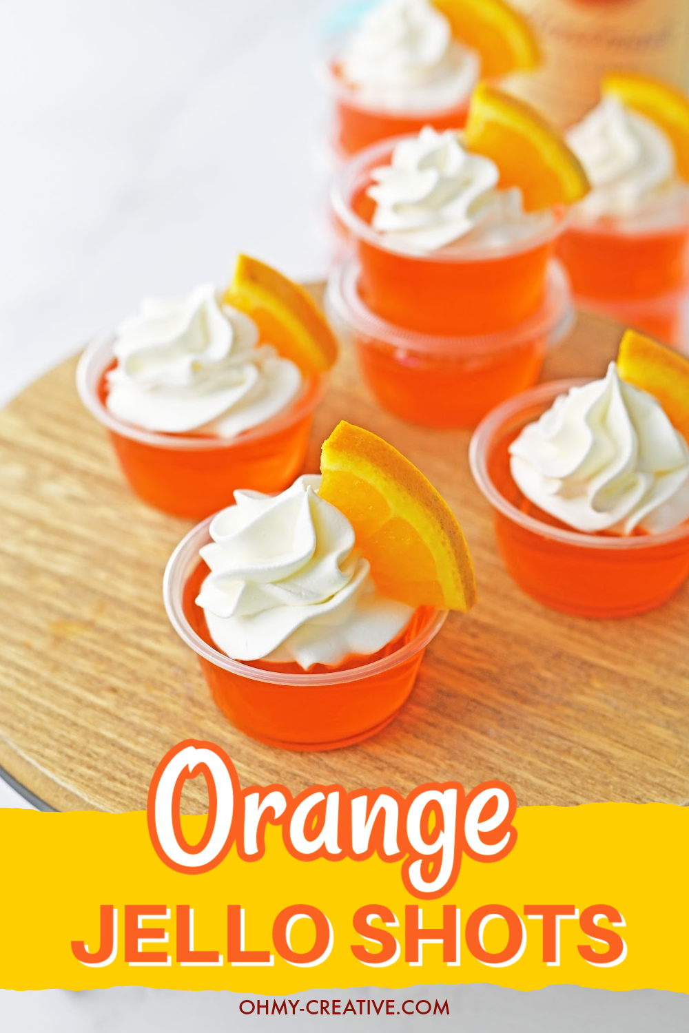 pin image that reads orange jello shots with several jello shots in plastic containers topped with whipped cream and a slice of orange