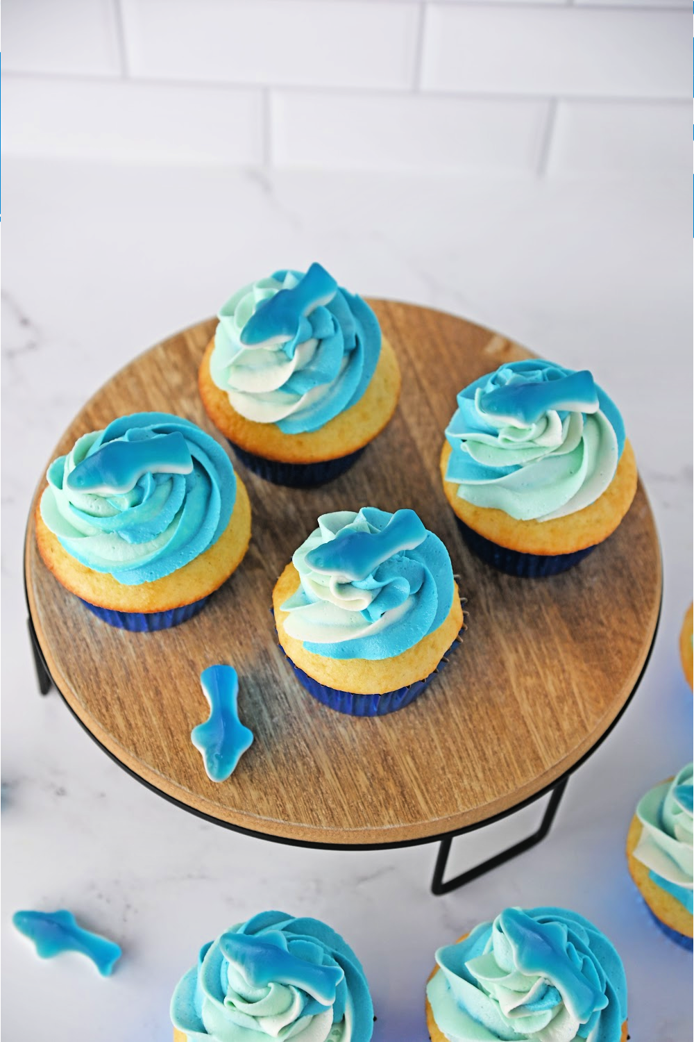 Looking from above at homemade shark cupcakes with ombre blue icing and gummy sharks.