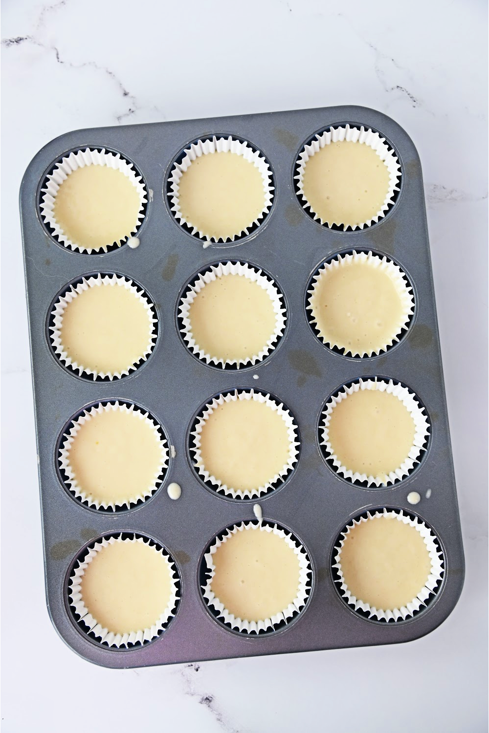 white cupcake batter in muffin pan.