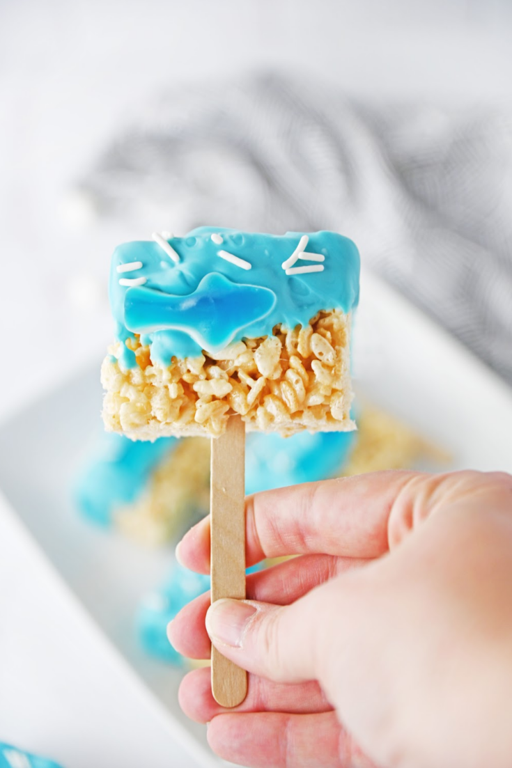 These adorable shark Rice Krispie treats have the prettiest blue colors and are easy to serve at parties. Kids love them! Since they are served on sticks like cake pops, these shark Rice Krispie treats are the perfect shark party dessert or snack. They are also the great Shark Week treats!