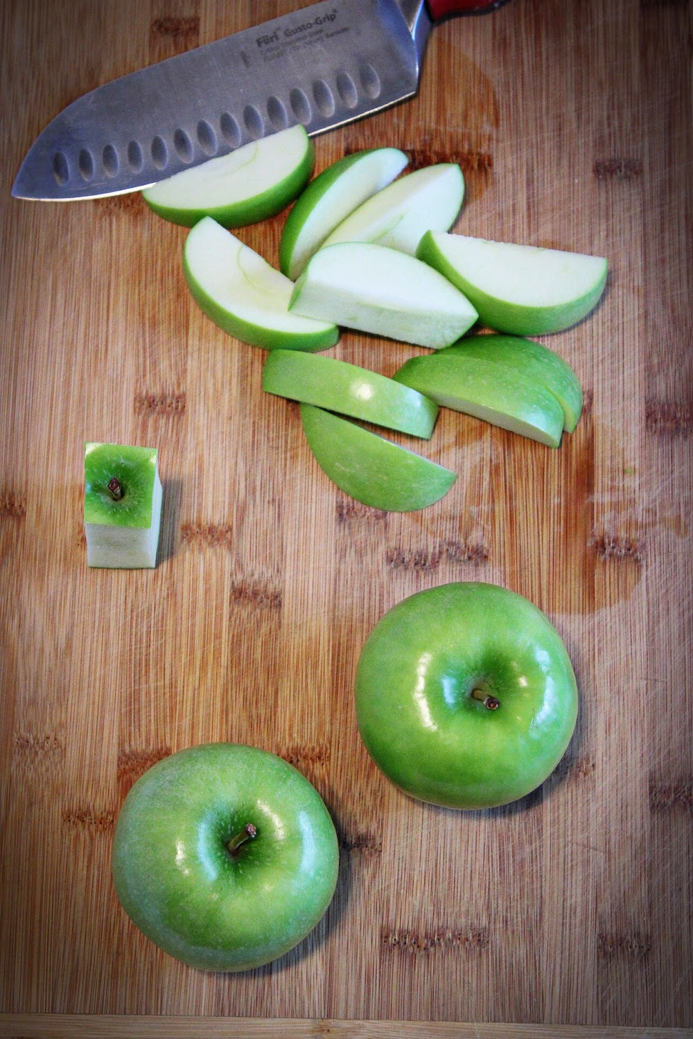 Whole apples and slice green apples on a cutting board.
