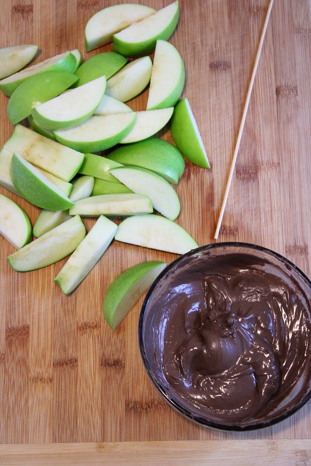 Melted bowl of chocolate and slices of green apples for dipping.