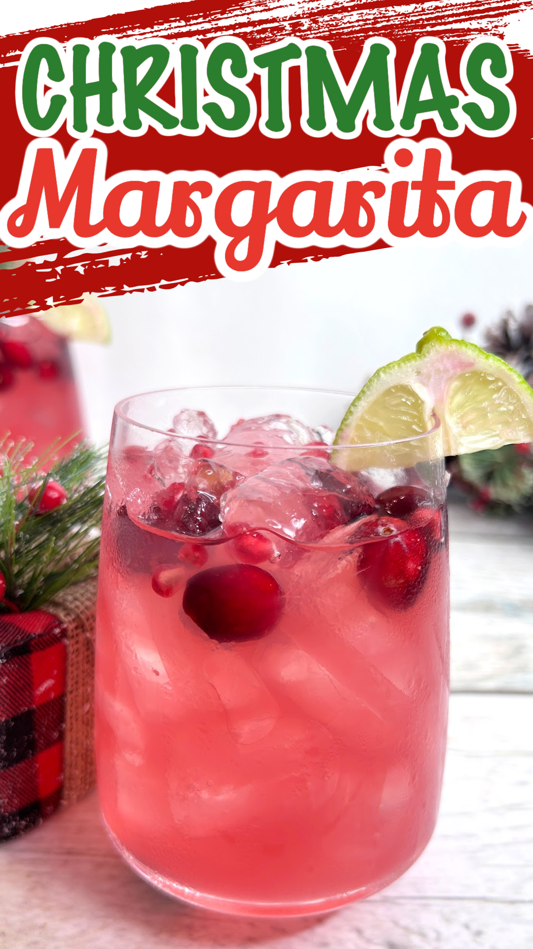 Pin image of a Christmas margarita with fresh cranberries and a lime wedge as garnish. Holiday margarita made with cranberry juice and pomegranate juice.