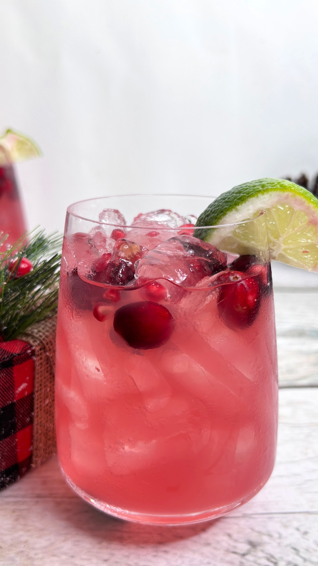 Image of a Christmas margarita with fresh cranberries and a lime wedge as garnish.