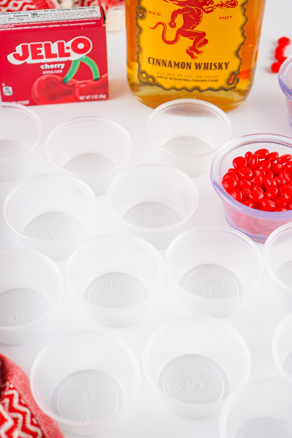 Clear jello shot cups with some fireball jello shot ingredients in the background.