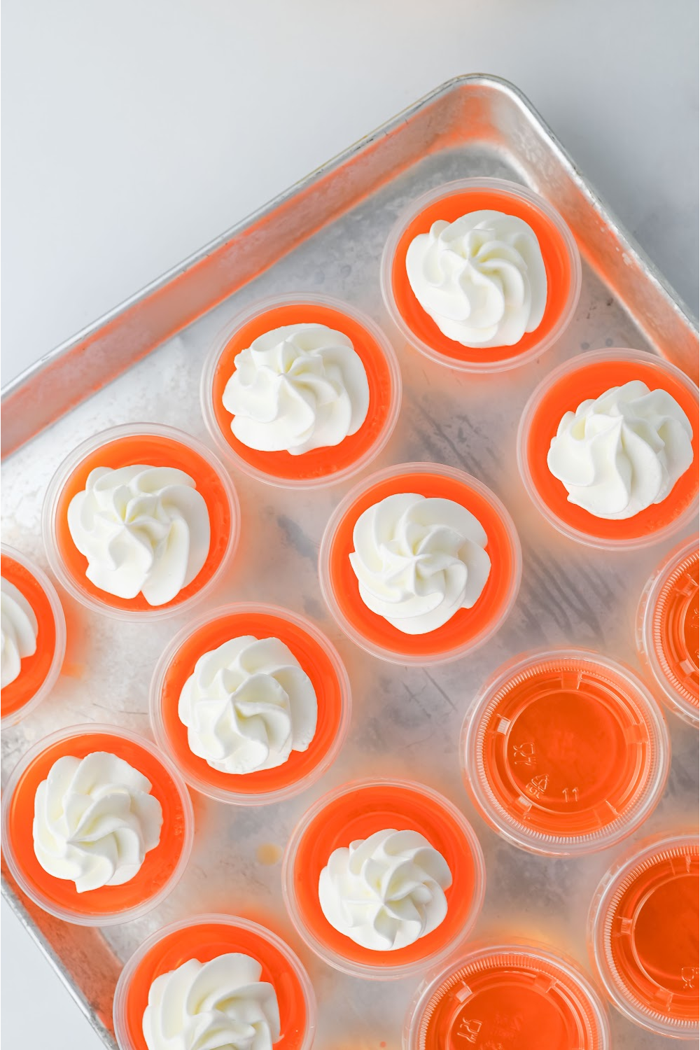 With the jello shots on a tray, decorate with whipped cream and add a cherry on top.