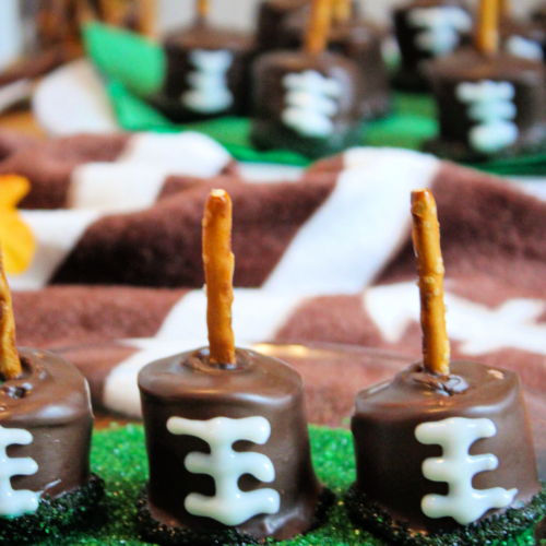 Pin image of Football Marshmallow pops. These game day treats are sitting in a dish of green sprinkle sugar.