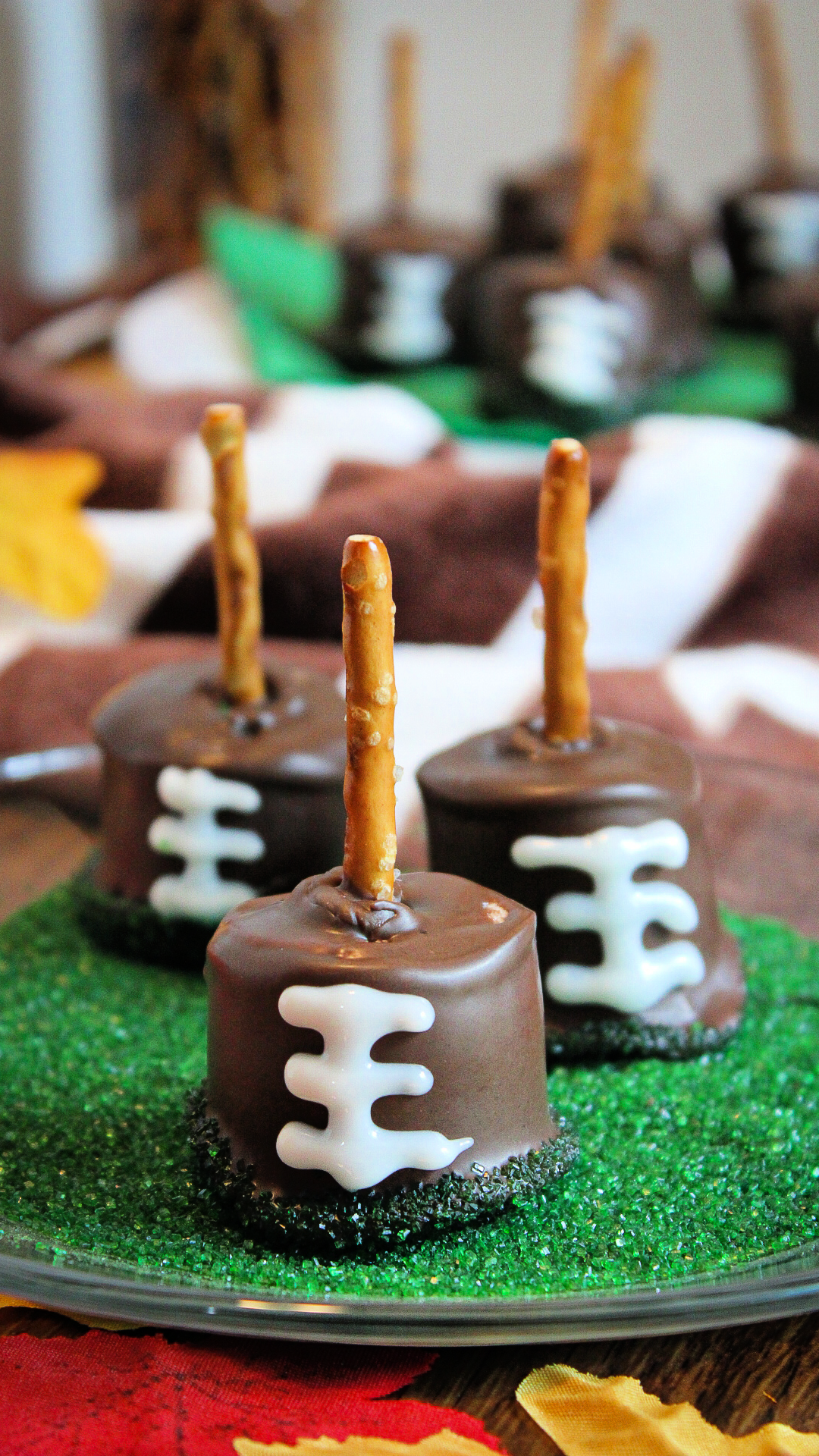 Pin image of Football Marshmallows. These game day treats are sitting in a dish of green sprinkle sugar.