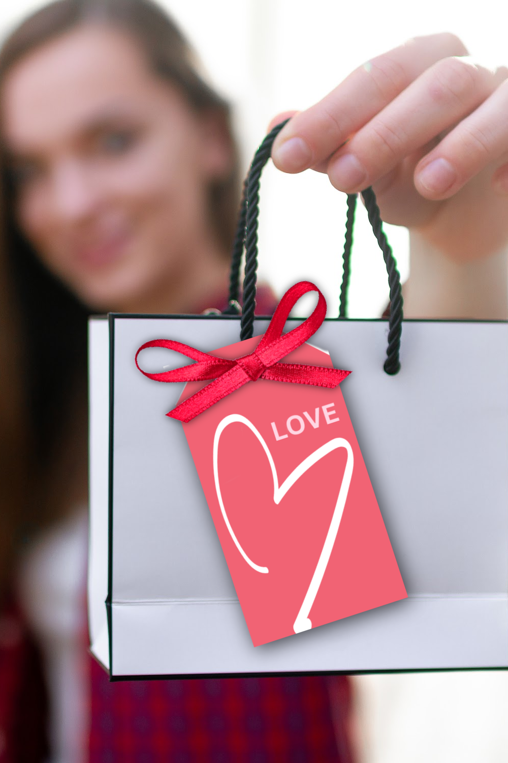 A white gift bag with a printable pink Valentine's Day gift tag with a heart graphic and the word LOVE.