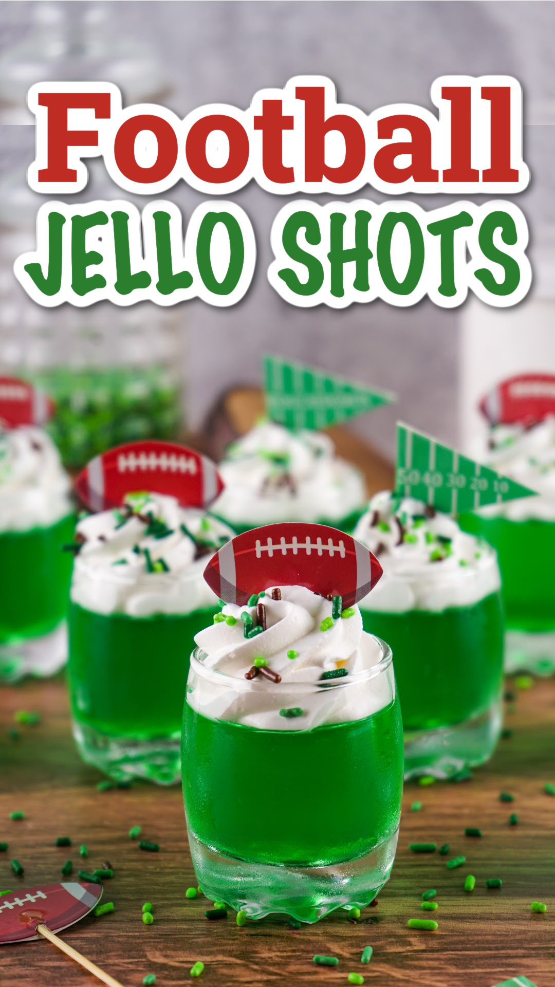 Green jello shots topped with whipped cream with brown and green sprinkles and football toppers. The perfect game day football jello shots!
