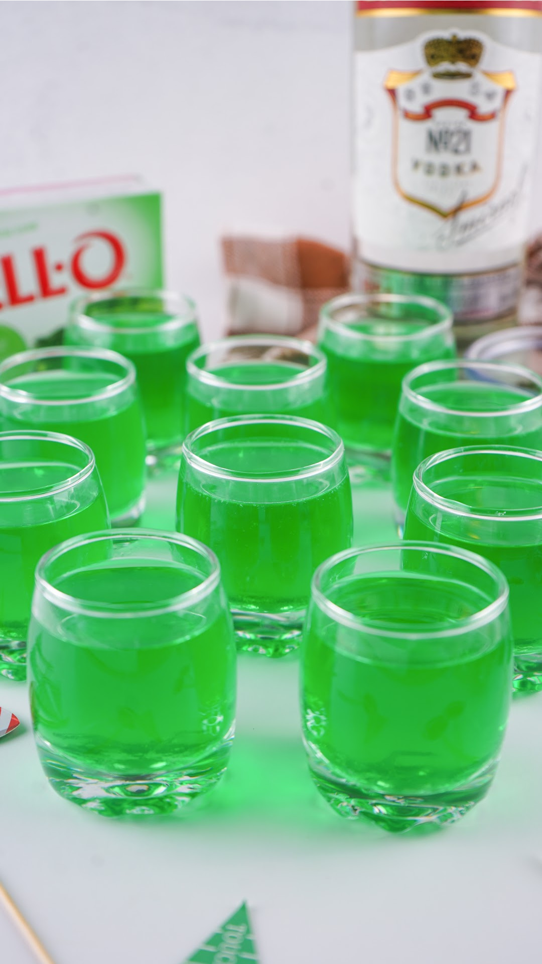 How to make Green jello shots topped with whipped cream with brown and green sprinkles and football toppers. The perfect game day football jello shots!