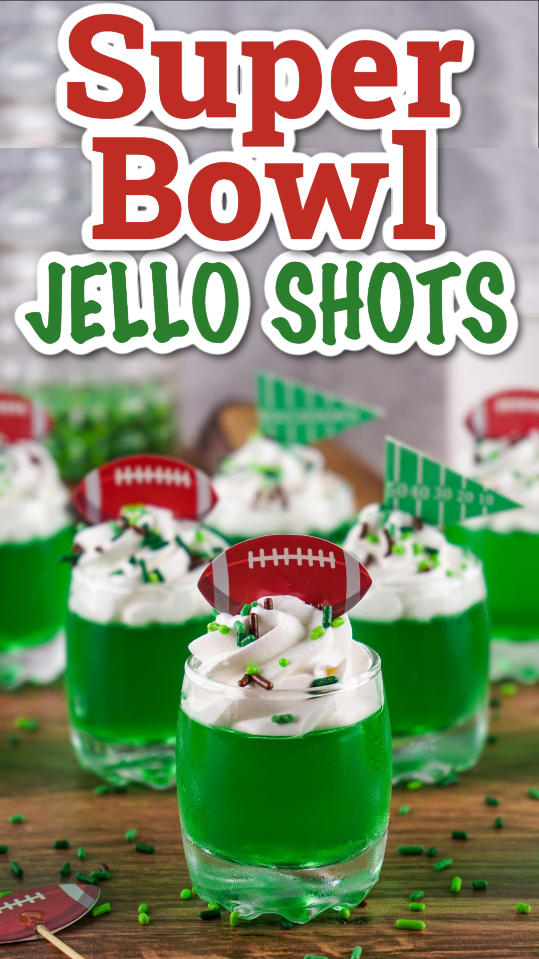 Super Bowl green jello shots topped with whipped cream with brown and green sprinkles and football toppers. The perfect game day football jello shots!