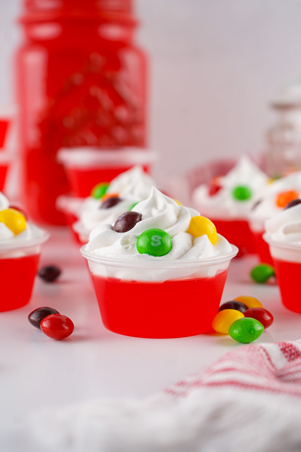 Skittles jello shots topped with cool whip and a sprinkle of Skittles.