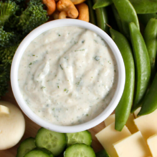 A veggie yogurt dip surrounded by cheese and veggies.