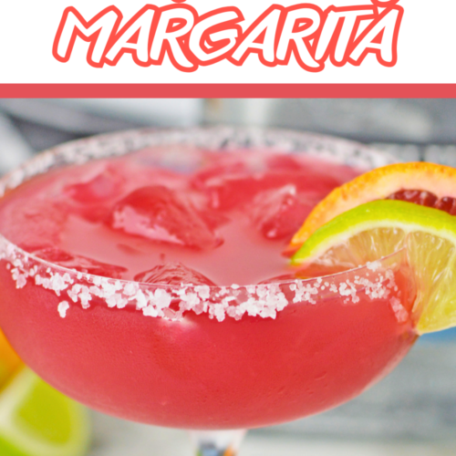 A vibrant glass of blood orange margarita filled with ice and garnished with lime and blood orange slices. The rim of the glass is coated with coarse salt. The text on the image reads 'The Best Blood Orange Margarita' with the website 'ohmy-creative.com' at the bottom.