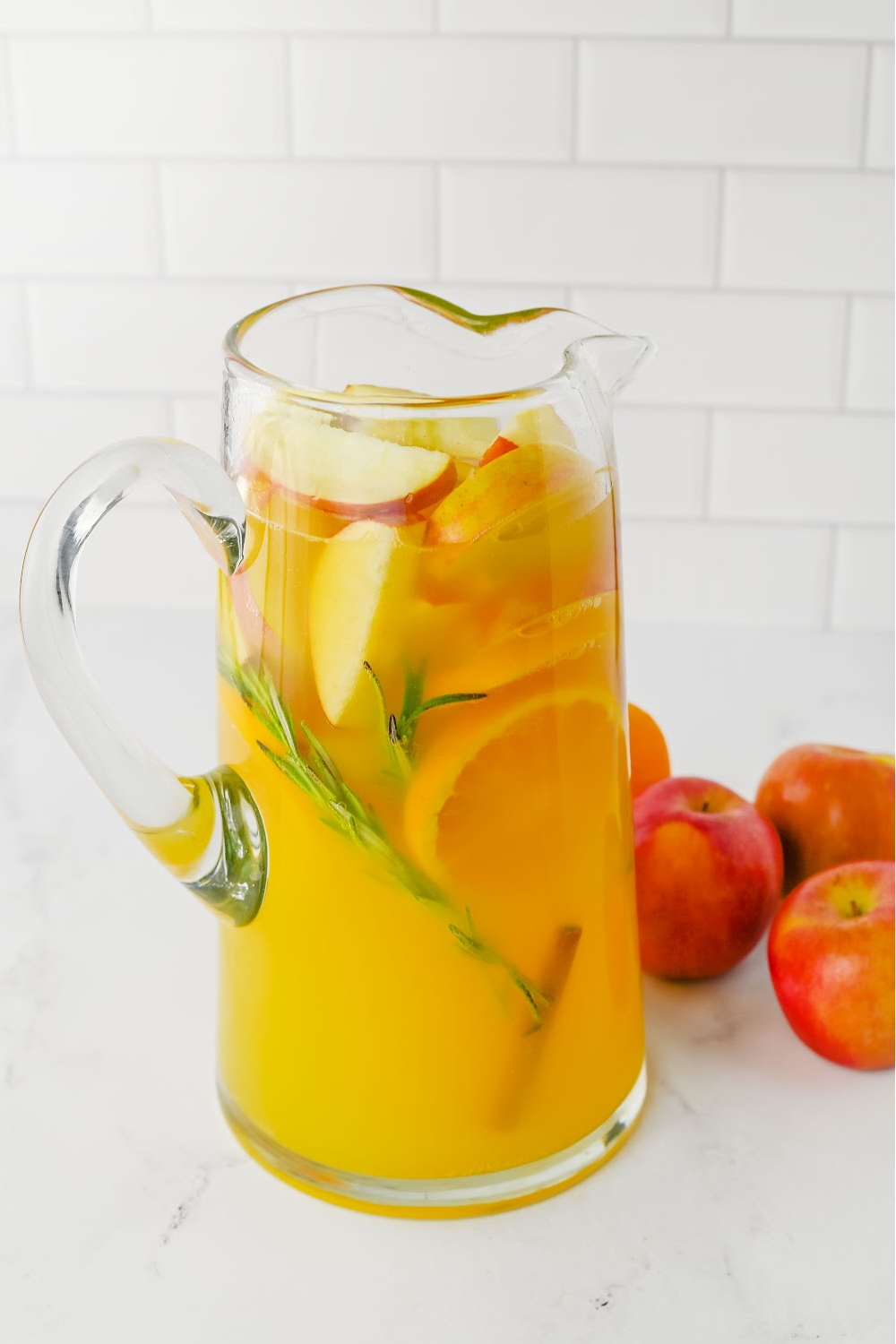 Finished pitcher of harvest punch with sliced fruit.