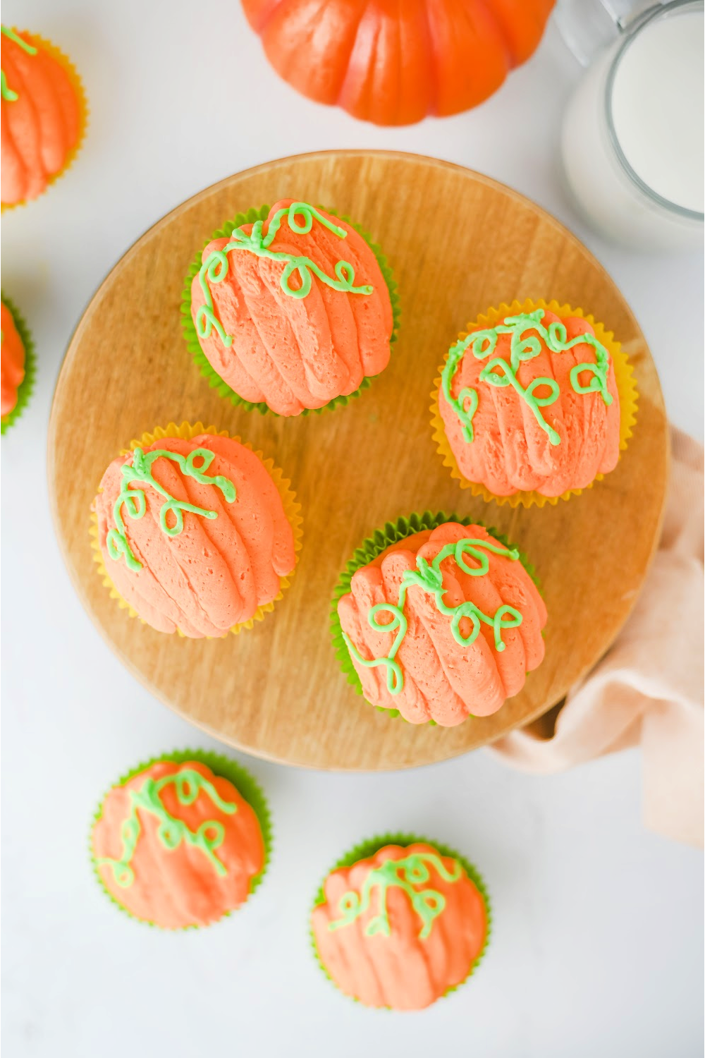 Looking down on a tray of pumpkin decorated cupcakes with green vines.
