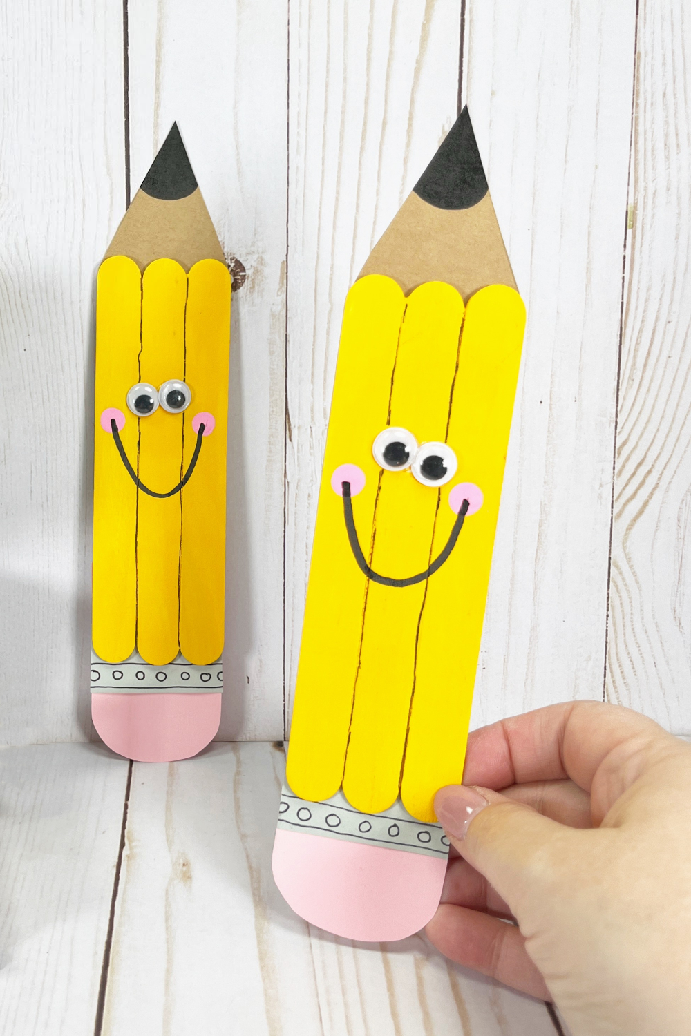 A hand holding a finished pencil craft made with craft sticks for the dollar store.