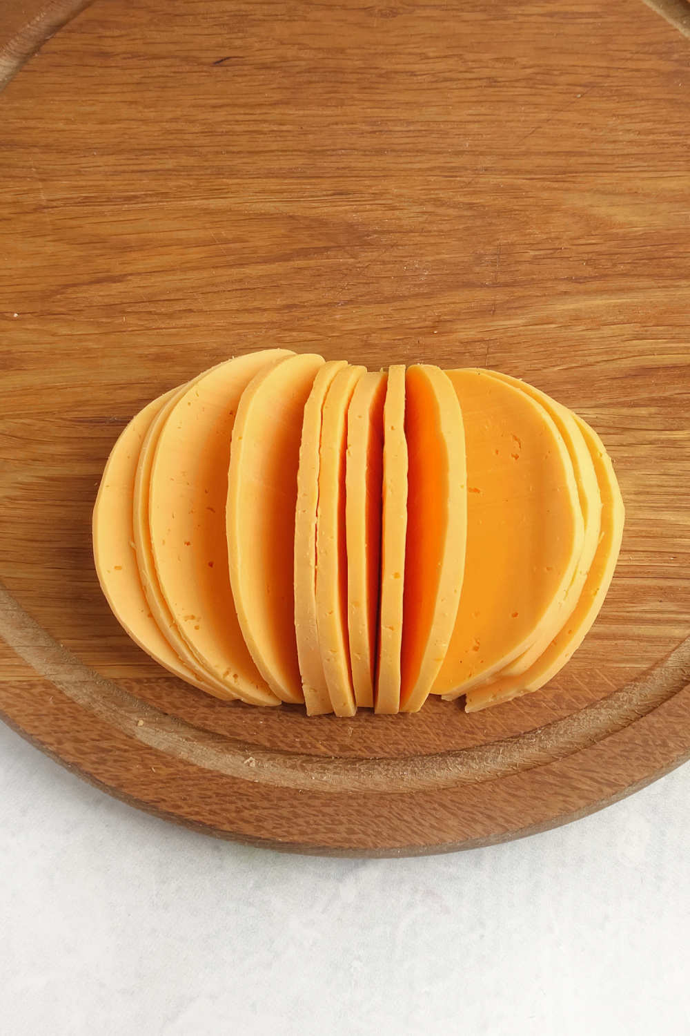 sliced cheddar cheese shaped to look like a pumpkin on a wood tray.